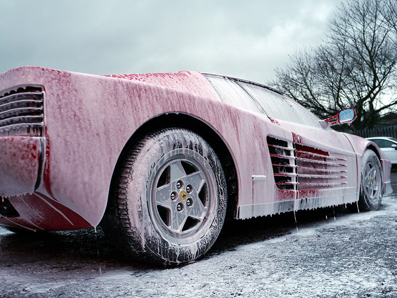 Car Wash from Spray Gun with Foam Aimed at the Car Wheel Stock